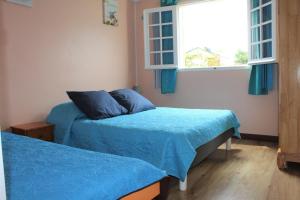 a bedroom with two beds with blue sheets and a window at CASAMELIAS "Le camélia" in Cilaos