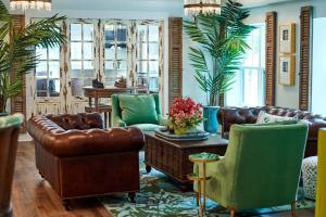 a living room with brown leather furniture and green chairs at Hotel Simone in Saint Simons Island