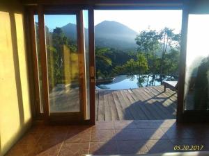 une porte ouverte sur une terrasse offrant une vue sur la piscine. dans l'établissement DWan Tea Mountain Side, à Jatiluwih