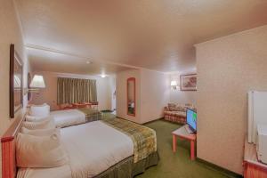 a hotel room with a large bed and a television at Brandin' Iron Inn in West Yellowstone
