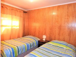 Habitación con 2 camas y paredes revestidas de madera. en Casa Amoblada Frutillar en Frutillar