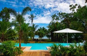 
a beach area with a pool, chairs, and umbrellas at Le Cameleon Boutique Hotel in Puerto Viejo

