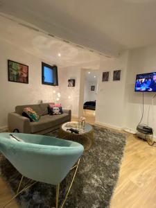 a living room with a couch and a tv at Joli appartement avec cour privée proche gare & centre ville in Rouen