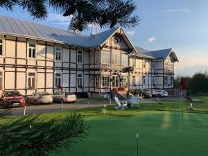 un grand bâtiment avec un putting-green devant lui dans l'établissement Kurhotel Tivoli, à Tatranská Polianka