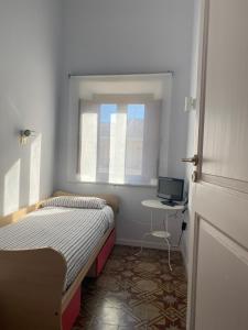 a small room with two beds and a desk and a window at Cortile Umberto in Racalmuto