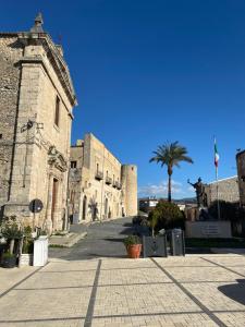 a building with a palm tree in the middle of a street at Cortile Umberto in Racalmuto