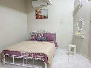 a bedroom with a bed with purple sheets and a mirror at AUNI & AUJI HOMESTAY KEMAMAN in Kemaman