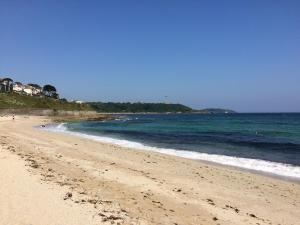 a sandy beach with the ocean and houses in the background at No.10 Falmouth - 2 minutes walk to the beach in Falmouth