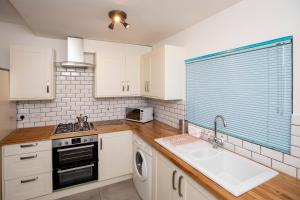 una cocina con armarios blancos y fregadero en Arthouse - Lovely, Spacious and Elegant 5bed House en Nottingham
