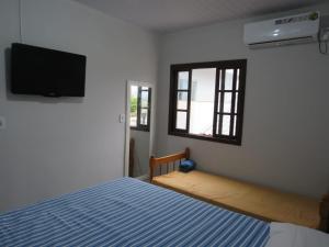 a bedroom with a bed and a flat screen tv at Residencial Coração do Mar in Palhoça