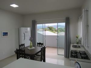 a kitchen with a table and a kitchen with a view at Residencial Coração do Mar in Palhoça