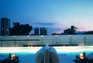 a person laying on a pool with a view of a city at Habita, Mexico City, a Member of Design Hotels in Mexico City