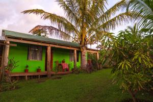 una casa verde con palmeras delante en Cabañas Nua e Koro, en Hanga Roa