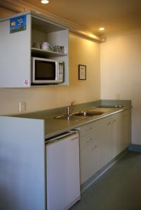 a kitchen with a sink and a microwave at Colonial Lodge Motel in Taupo