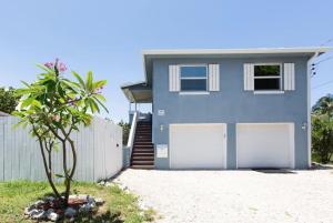 a blue house with two white garage doors at Light and Breezy in SoSo in West Palm Beach