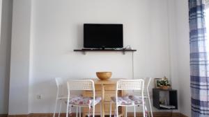 mesa de comedor con sillas y TV en la pared en Torrox Costa, en Torrox Costa