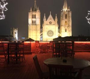 a lit up cathedral with tables and chairs at night at Camarote Hotel in León