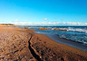 una playa de arena con olas y rocas en el océano en LA PALOMA CONTAINERS SUITES, en La Paloma