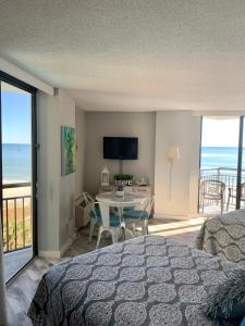 a bedroom with a bed and a table with a view of the ocean at 426 Belle Vue Magnificent Oceanfront studio with two balconies in Myrtle Beach