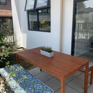 a wooden table and bench in front of a house at De la Plage Residences in Orewa