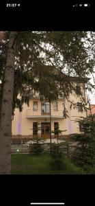 una gran casa blanca con un árbol delante en Готель Баронський Двір en Chernivtsi