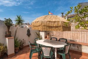 een patio met een tafel en stoelen en een rieten parasol bij Palazzo Arcidiacono - luxury holidays in Catania