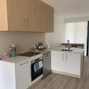 a kitchen with white cabinets and a sink at De la Plage Residences in Orewa