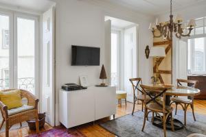 a living room with a table and a tv at Apartamento do Carmo in Lisbon
