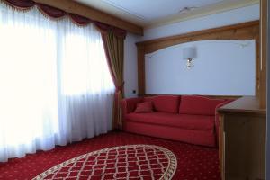 un soggiorno con divano rosso e finestra di Hotel Belvedere Srl a Fai della Paganella