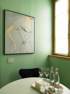 un tavolo con bicchieri da vino e un dipinto sul muro di Petronilla - Hotel In Bergamo a Bergamo