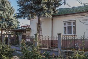 a white house with a fence and a tree at Villa Apartman in Makó