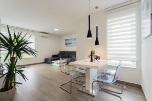 ein weißes Wohnzimmer mit einem Tisch und Stühlen in der Unterkunft New Modern Apartment "Marjan" in Podstrana