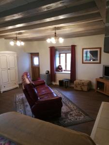 a living room with a leather couch and a tv at Chez Pastuso in Brigueuil-le-Chantre