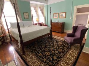 um quarto com uma cama e uma cadeira em Foley House Inn em Savannah