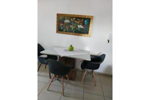 a table with chairs and a painting on the wall at Apartamento Cidade Verde 6 MT in Maringá