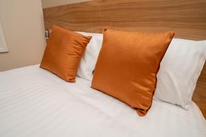 a bed with two orange pillows on top of it at Eagle Hotel Luton Airport in Luton