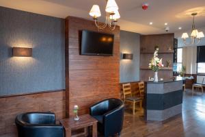 a bar with leather chairs and a television on a wall at Eagle Hotel Luton Airport in Luton +10 photos