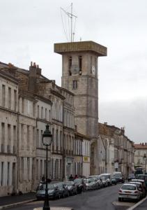un edificio con una torre dell'orologio in cima a una strada di Cœur de Ville a Rochefort