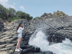 a woman standing on rocks in front of a waterfall at Quy Nhon Homestay BnB in Quy Nhon