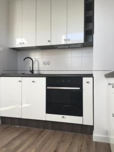 a kitchen with white cabinets and a black oven at Apartament45 in Giżycko