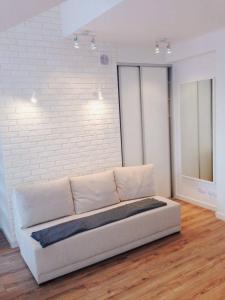 a white couch in a room with a brick wall at Apartament45 in Giżycko