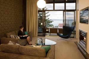 Vue Apartments في نابيير: امرأة تجلس على أريكة في غرفة المعيشة