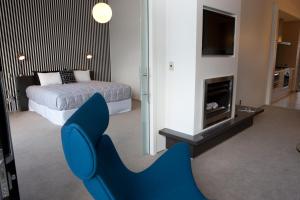 Vue Apartments في نابيير: كرسي ازرق في غرفة مع سرير ومدفأة