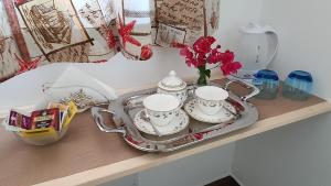 a table with two tea sets and a tray with flowers at DOMU NOSTA di Giulio & Ignazia Room3 in Santa Luria