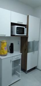 a white kitchen with a microwave and a refrigerator at Plaza Fraga Maia in Feira de Santana