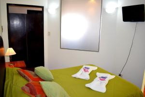 Un dormitorio con una cama verde con toallas. en Departamento Salta mi Ciudad 1 en Salta