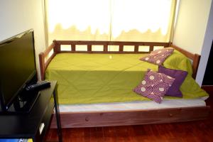 Cama con sábanas verdes y almohadas junto a una ventana en Departamento Salta mi Ciudad 1, en Salta