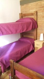 two bunk beds in a room with purple sheets at Cabañas Alma Comechingon in Villa Cura Brochero