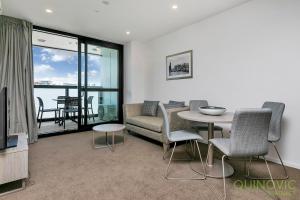 a living room with a couch and a table and chairs at QV Stays City Central Apartment with Parking in Auckland