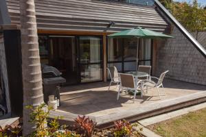 a patio with a table and an umbrella at Pioneer Waterfront Apartments in Paihia